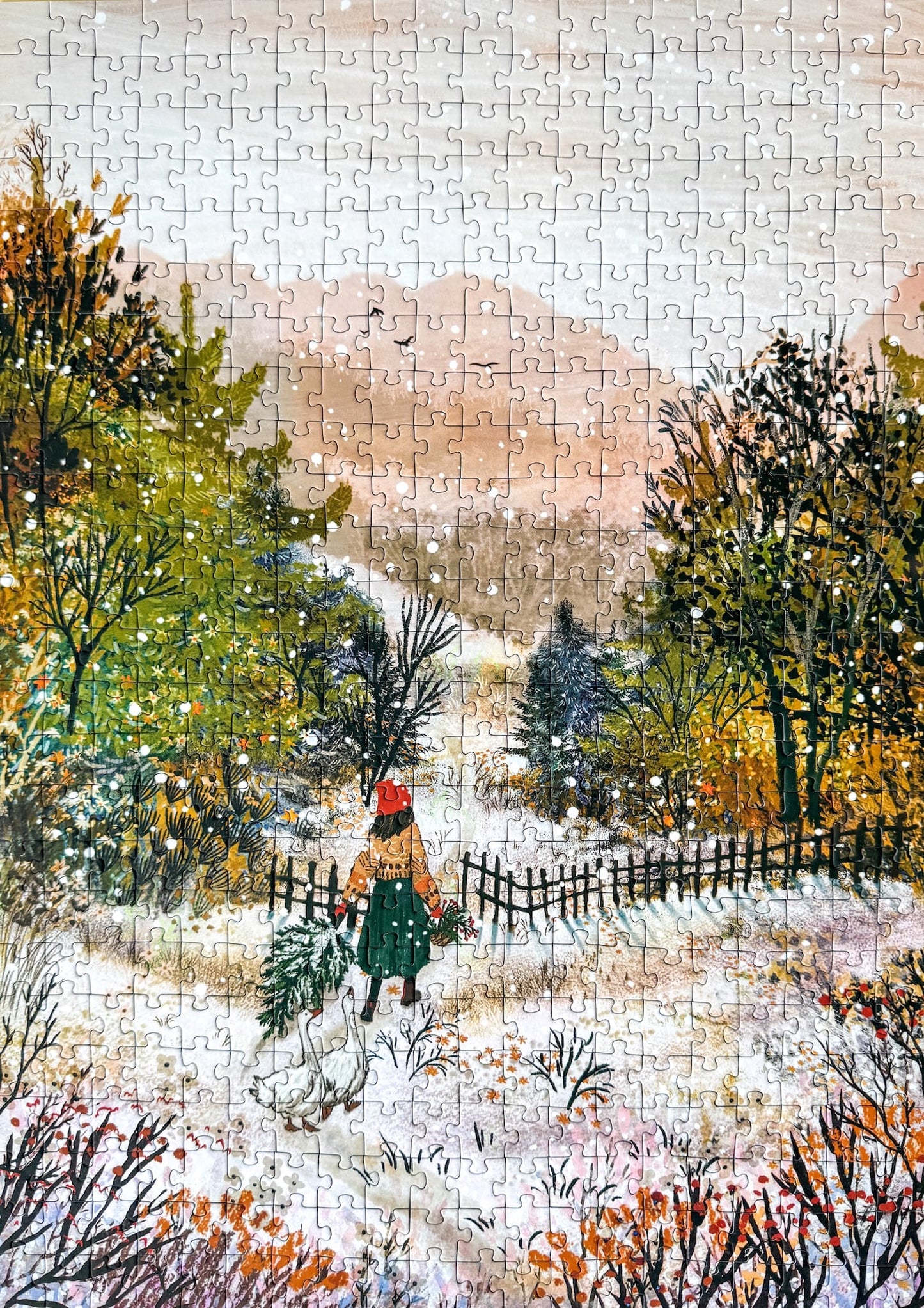 500-Teile-Puzzle „Homecoming“ von Piecely – Illustration einer winterlichen Landschaft mit Frau und zwei Gänsen auf einem verschneiten Weg, auf grauer Verpackung.