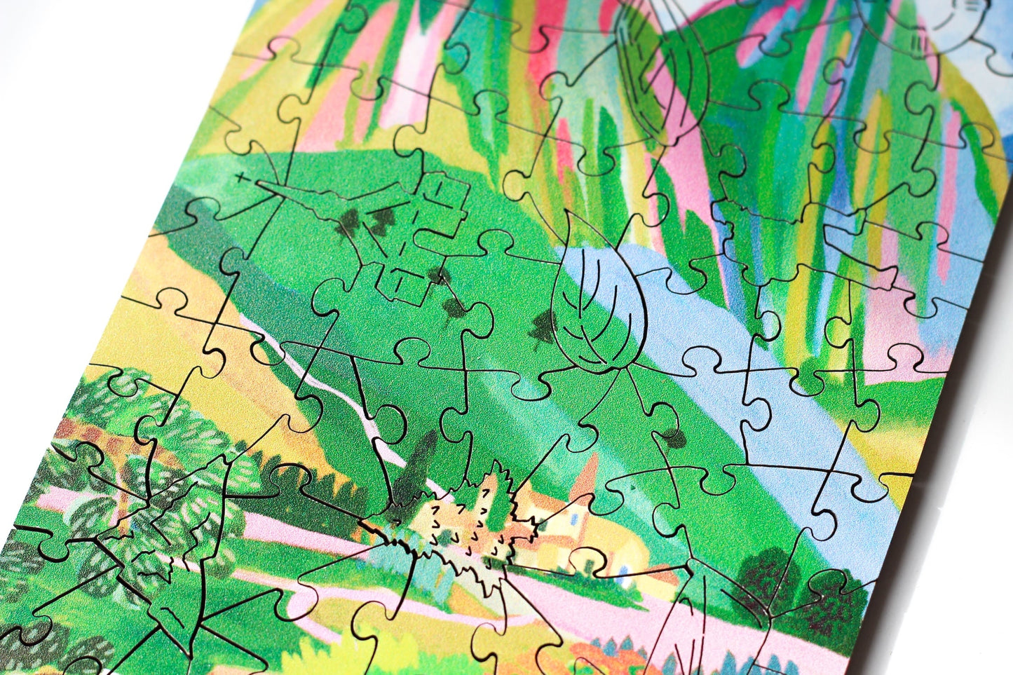 80-Teile-Holzpuzzle „The Dolomites“ von Piecely – farbenfrohe Illustration einer Berglandschaft mit Dorf und Blumen von Hebe Studio.