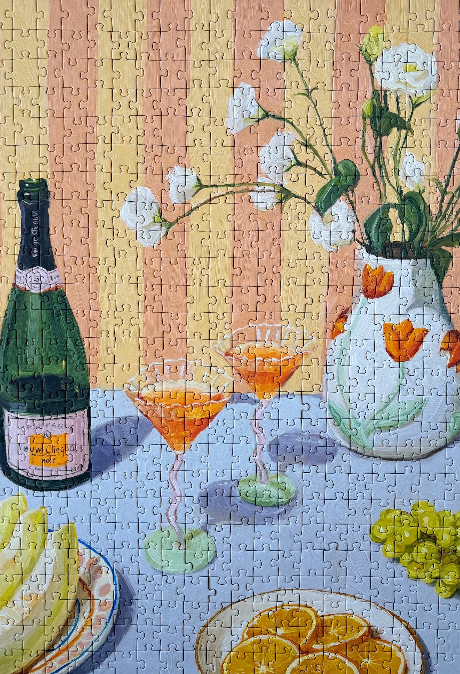 Illustration eines gedeckten Tisches mit Getränken, Orangen, Trauben und Blumen in Vase, als 500-Teile Puzzle ‚Love At First Sip‘ von Piecely