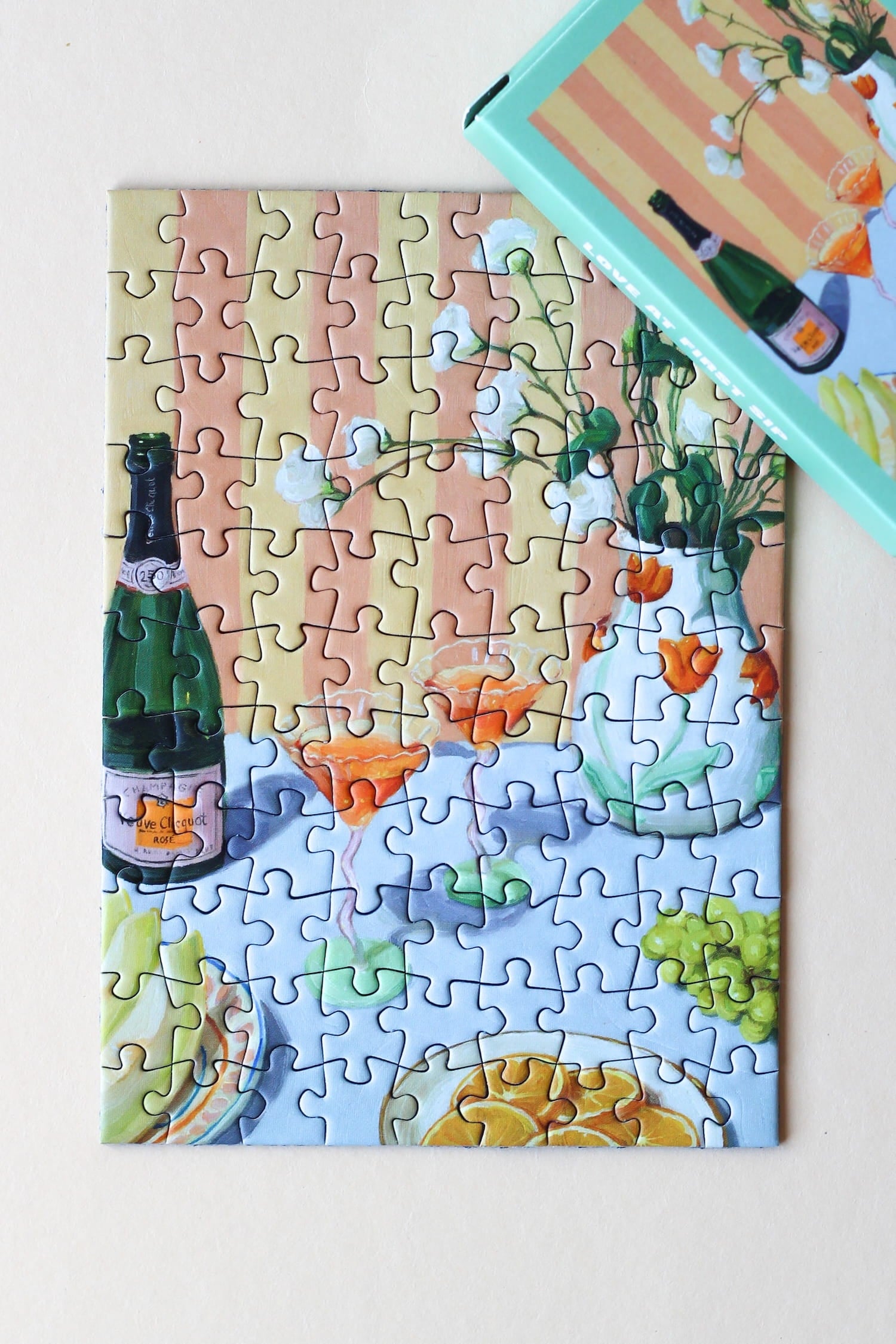 Illustration eines gedeckten Tisches mit Drinks, Orangen, Trauben und Blumen, als 99-Teile Minipuzzle ‚Love At First Sip‘ von Piecely
