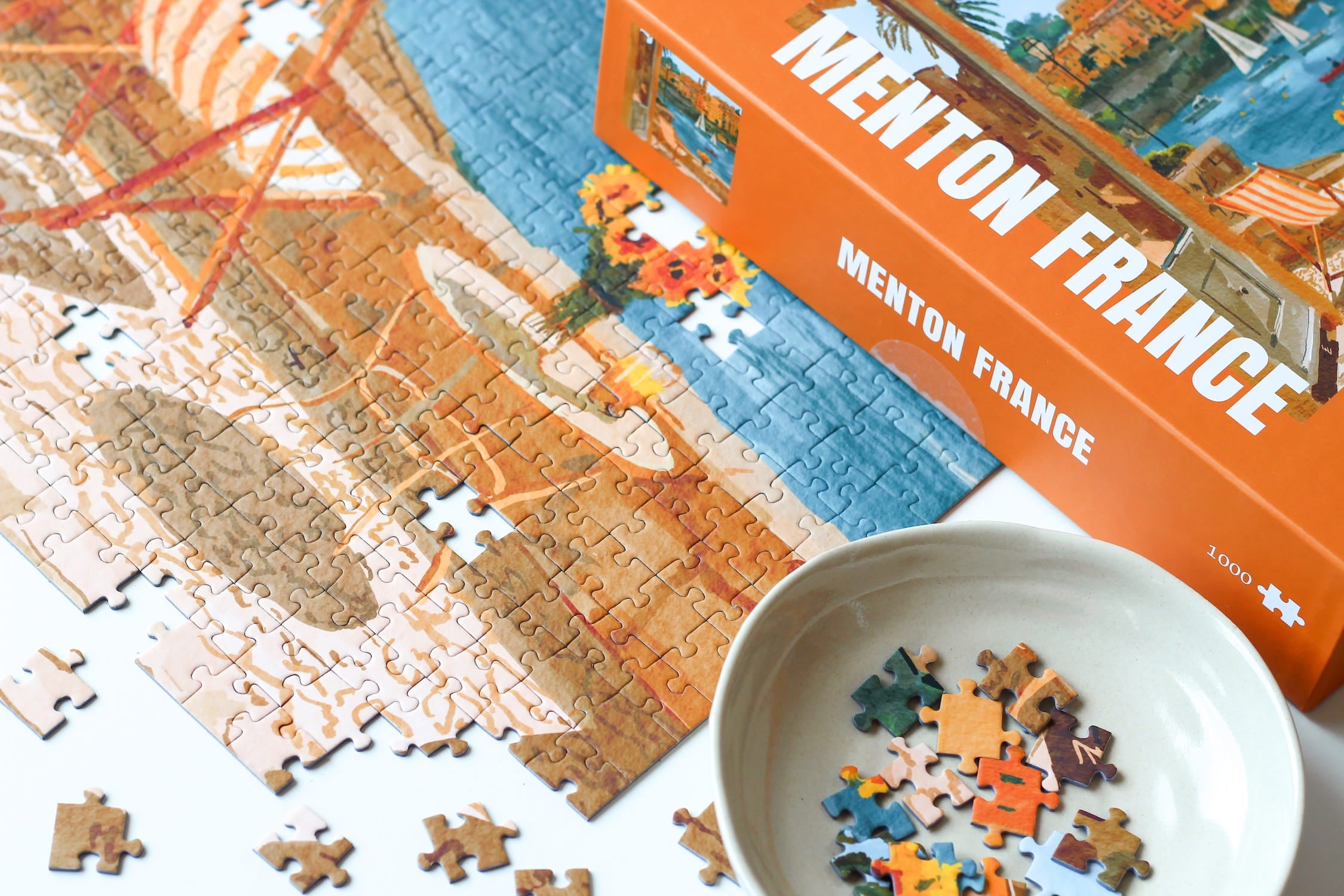 Illustration eines Balkons mit Blick auf das Meer, Segelboote und die Stadt Menton in Südfrankreich, als 1000-Teile Puzzle von Piecely