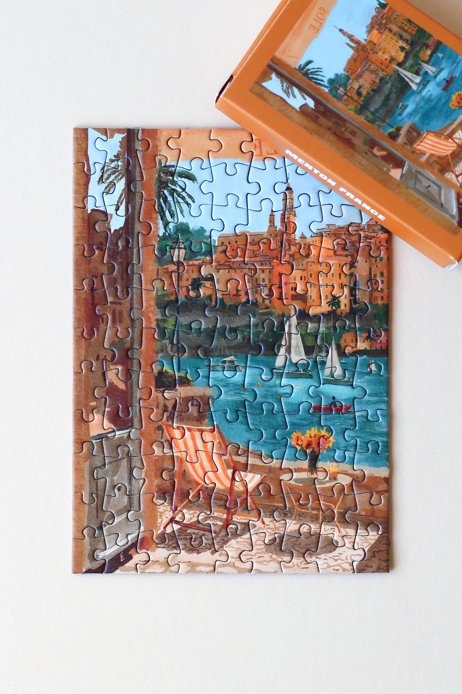 Illustration eines Balkons mit Blick auf Meer, Segelboote und die Stadt Menton in Südfrankreich, als 99-Teile Minipuzzle von Piecely