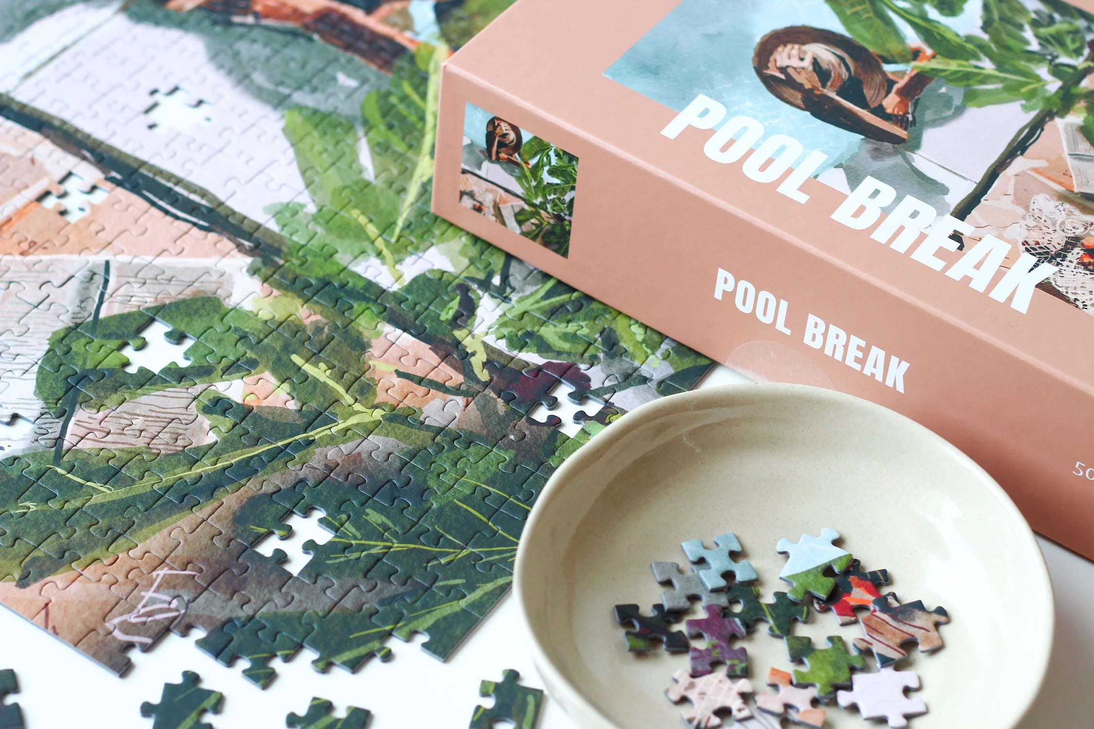 Illustration einer Frau am Pool mit Pflanzen und Buch in ruhiger Atmosphäre, als 500-Teile Puzzle ‚Pool Break‘ von Piecely