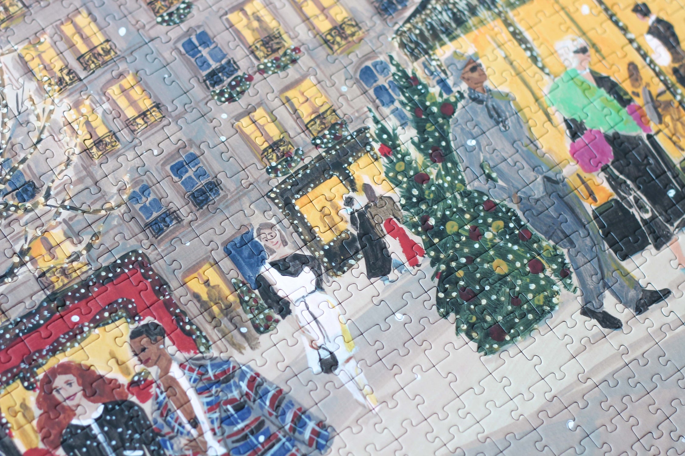 Plastikfreies Puzzle für Erwachsene, das Paris zur Weihnachtszeit zeigt. Stylisch gekleidete Menschen schlendern durch die Straßen und Bäume und Häuser sind mit leuchtenden Lichterketten geschmückt.