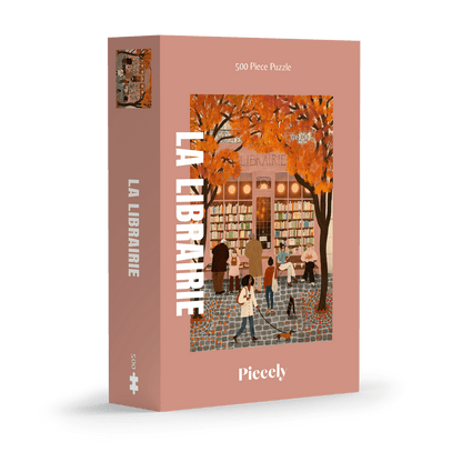 500-Teile-Puzzle „La Librairie“ von Piecely – Illustration einer herbstlichen Pariser Straßenszene vor einer kleinen Buchhandlung, auf rosa-brauner Verpackung.