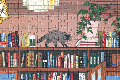 1000-Teile-Puzzle „Book Nook“ von Piecely – Illustration einer gemütlichen Bibliothek mit Bücherregalen, Lesenden und warmem Licht, auf brauner Verpackung.