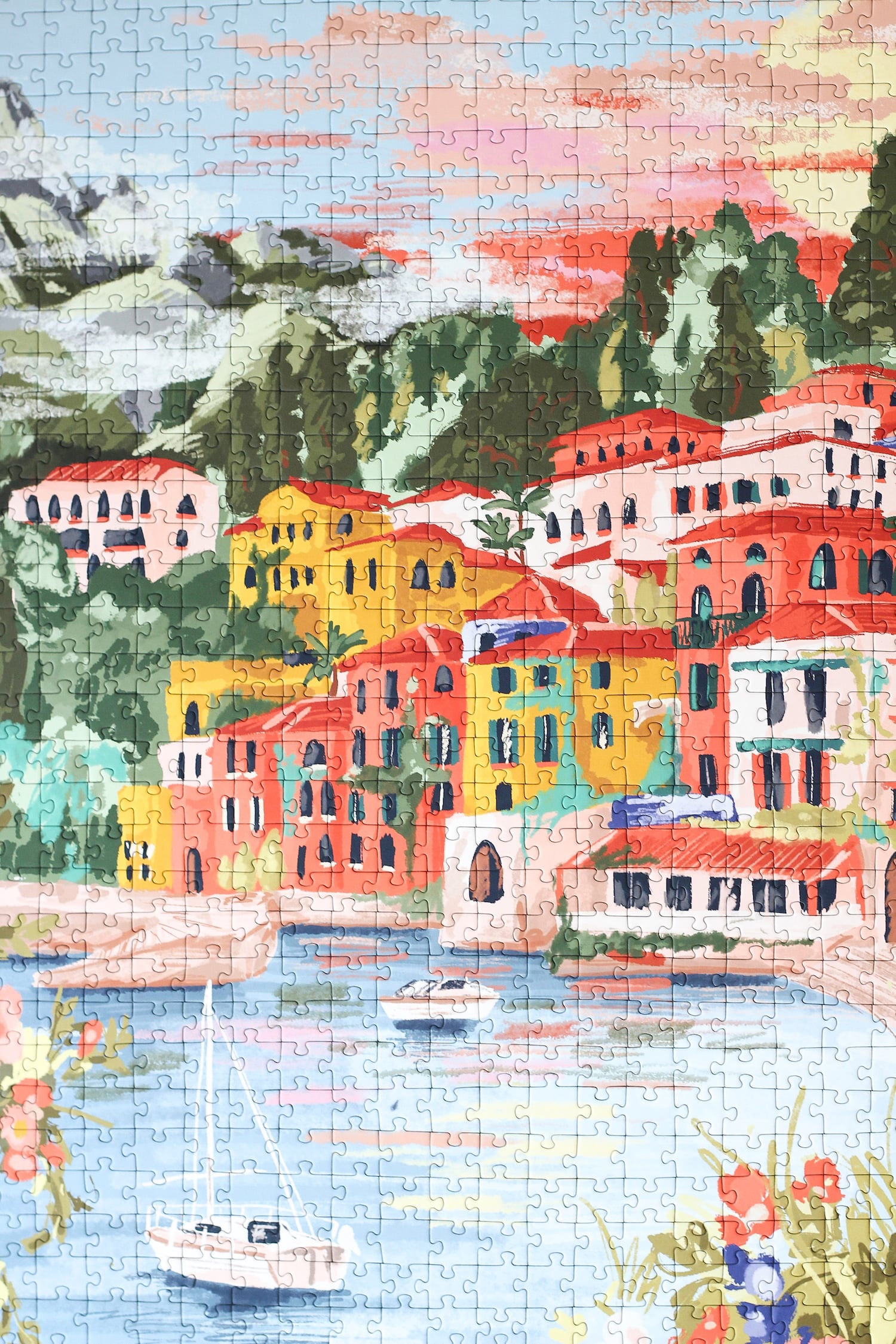 1000-teiliges Puzzle für Erwachsene, das den Comer See in Varenna zeigt. In der Bucht befinden sich zwei Boote und die Sicht auf den See ist gesäumt von bunten Häusern.