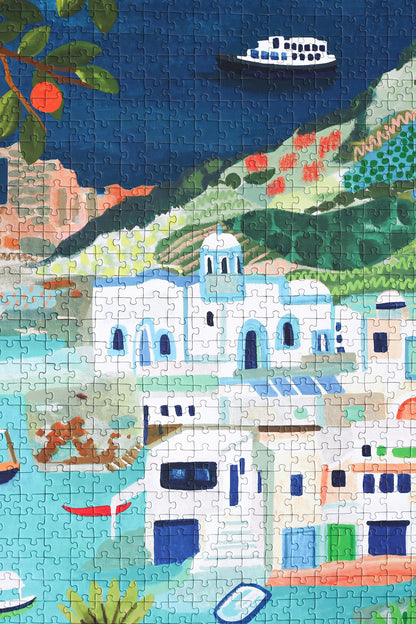 Außergewöhnliches 1000-Teile-Puzzle für Erwachsene, das einen Teil der griechischen Insel Milos zeigt. Zu sehen sind weiße Häuser and der Küste, Orangenbäume und Schiffe und Boote auf dem Meer.