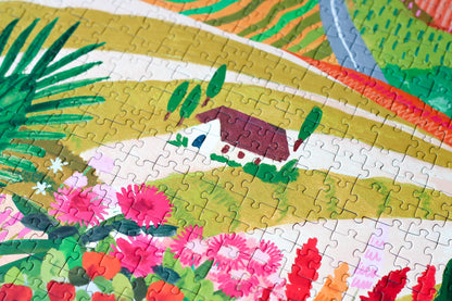 Außergewöhnliches 1000-Teile-Puzzle für Erwachsene, das die sommerliche Landschaft Apuliens in Italien zeigt. Zu sehen sind blühende Felder, Ein Berg und ein kleines Haus.