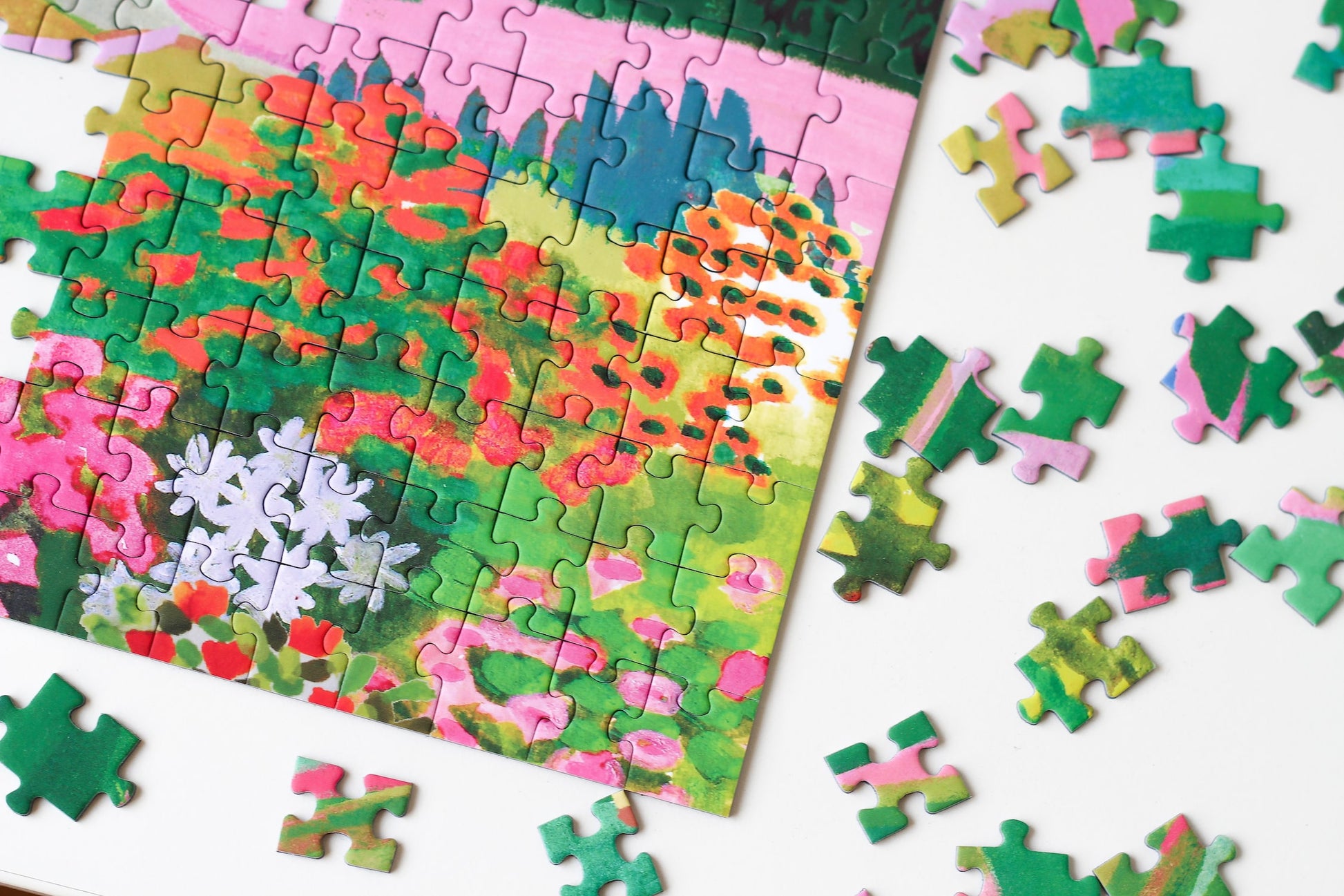 1000-Teile-Puzzle „The Dolomites“ von Piecely – Illustration einer farbenfrohen Berglandschaft in den Dolomiten mit Dorf und Blumen, auf türkisfarbener Verpackung.