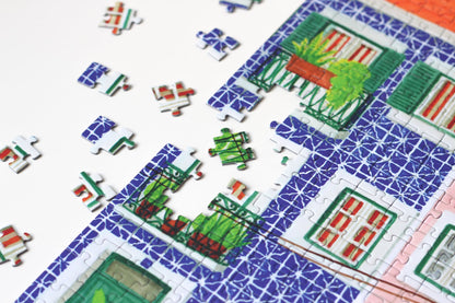 1000-Teile-Puzzle „Lisbon“ von Piecely – Illustration einer farbenfrohen Straßenszene in Lissabon mit gelber Straßenbahn und bunten Häusern, auf pinker Verpackung.