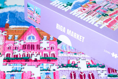 1000-teiliges Puzzle für Erwachsene, das den Weihnachtsmarkt in Riga zeigt. Auf dem Platz befinden sich pinke Stände und geschmückte Weihnachtsbäume.