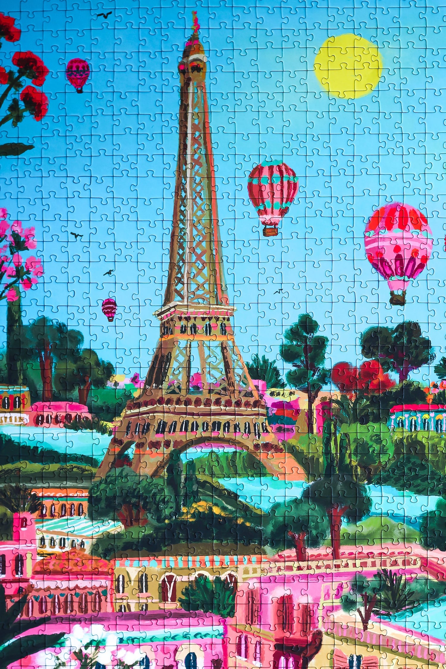 1000-teiliges Puzzle für Erwachsene, das den Eiffelturm in Paris zeigt. Die Sonne scheint, der Himmel ist blau und ind er Luft befinden sich mehrere Heißluftballons.