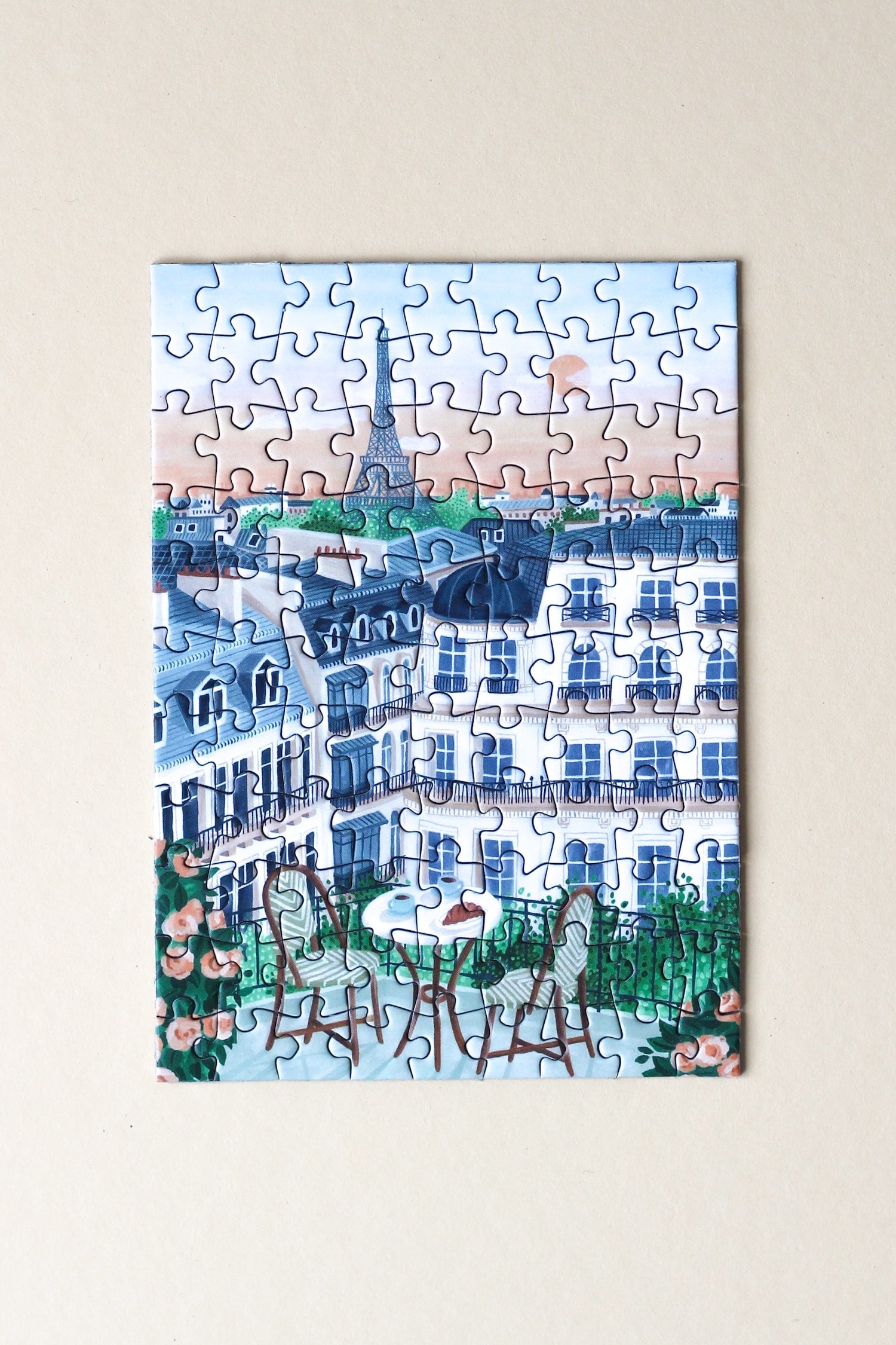 99-Teile-Mini-Puzzle „Paris“ von Piecely – Illustration eines Pariser Balkons mit Frühstückstisch, Rosen und Blick auf den Eiffelturm, auf hellblauer Verpackung.