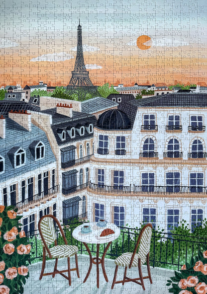 1000-Teile-Puzzle „Paris“ von Piecely – Illustration eines Pariser Balkons mit Frühstückstisch und Blick auf den Eiffelturm, auf hellblauer Verpackung.