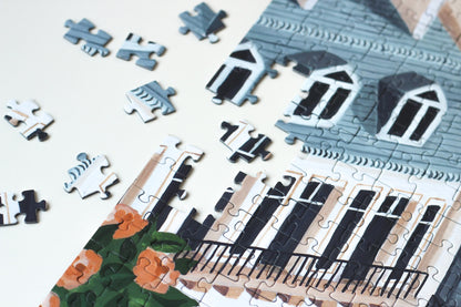 1000-Teile-Puzzle „Paris“ von Piecely – Illustration eines Pariser Balkons mit Frühstückstisch und Blick auf den Eiffelturm, auf hellblauer Verpackung.