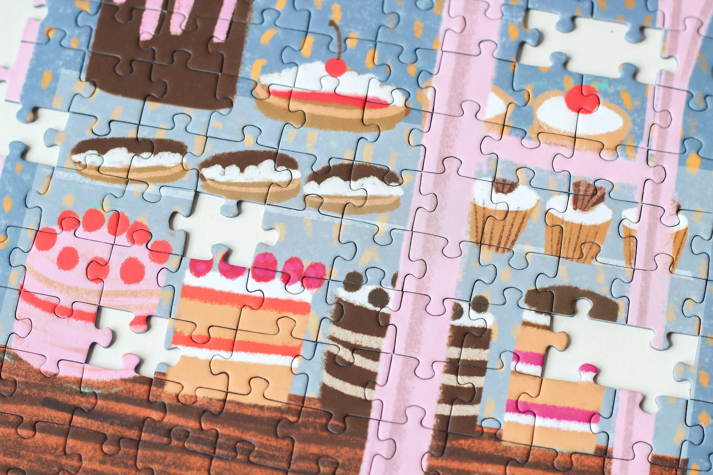 Außergewöhnliches 1000-Teile-Puzzle für Erwachsene, das eine rosa Bäckerei mit Torten, Kuchen und Cupcakes im Schaufenster und einen kleinen Hund für der Tür zeigt.