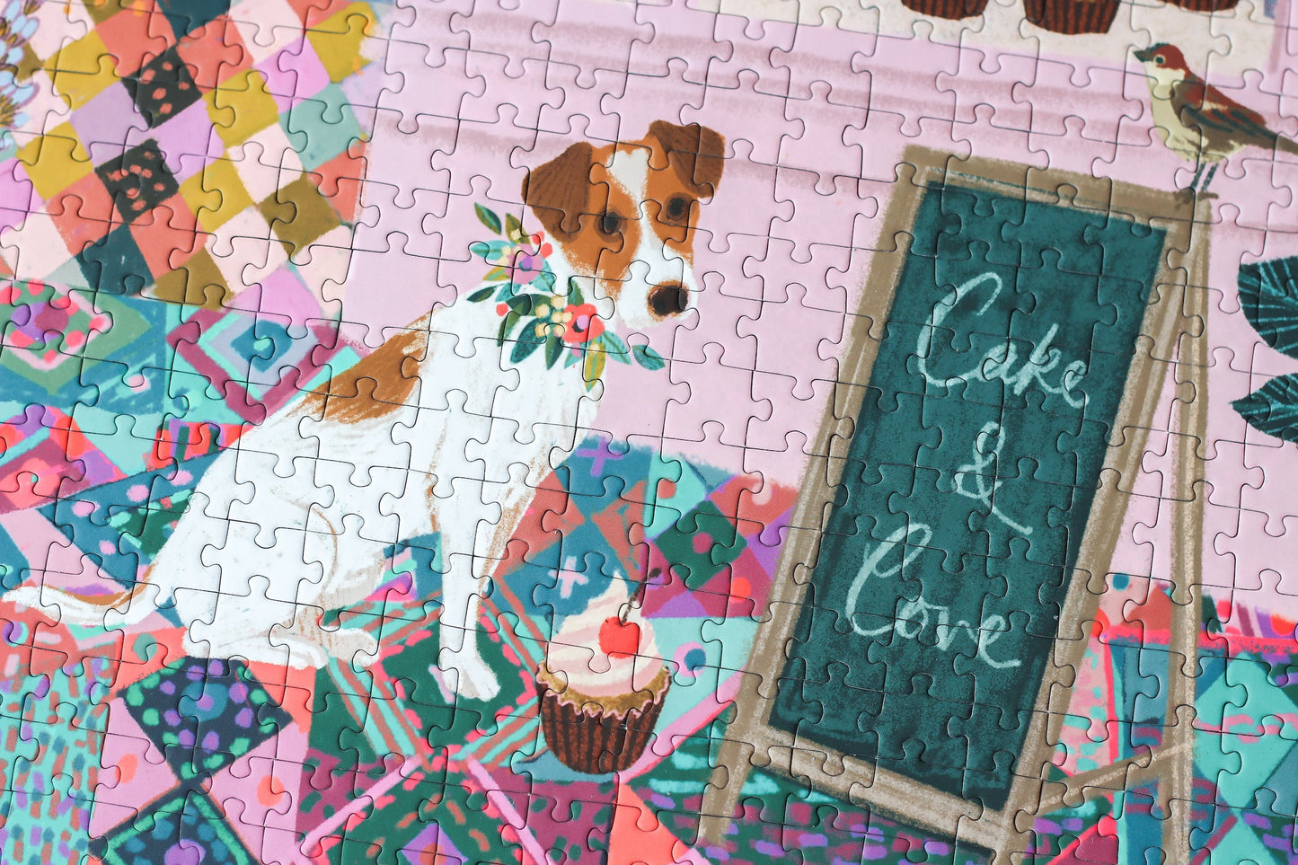 Außergewöhnliches 1000-Teile-Puzzle für Erwachsene, das eine rosa Bäckerei mit Torten, Kuchen und Cupcakes im Schaufenster und einen kleinen Hund für der Tür zeigt.