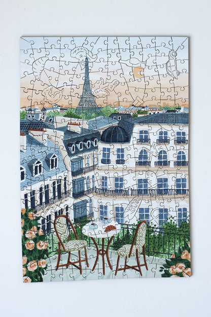250-Teile-Holzpuzzle „Paris“ von Piecely – Illustration eines Pariser Balkons mit Frühstückstisch, Rosen und Eiffelturm im Hintergrund, von Ellen Gözel-Niehoff.