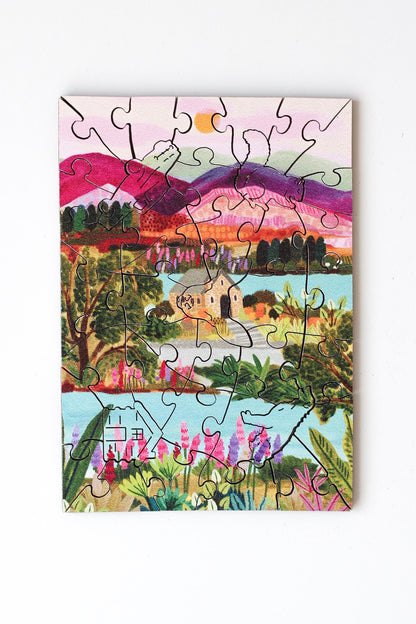 40-Teile-Holzpuzzle „Lake Tekapo“ von Piecely – Illustration einer neuseeländischen Landschaft mit Bergen, See und Kirche, von Hebe Studio.