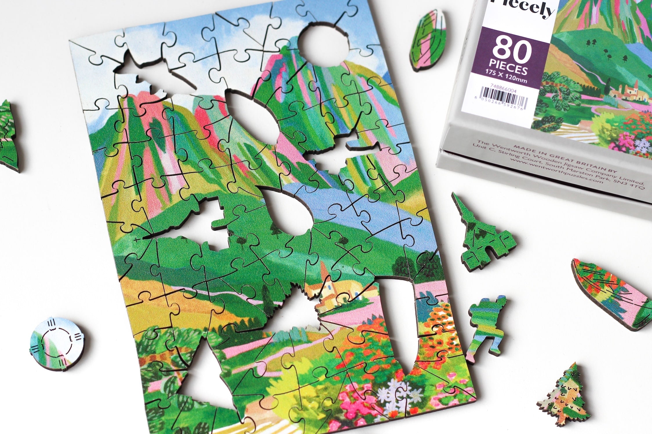 80-Teile-Holzpuzzle „The Dolomites“ von Piecely – farbenfrohe Illustration einer Berglandschaft mit Dorf und Blumen von Hebe Studio.