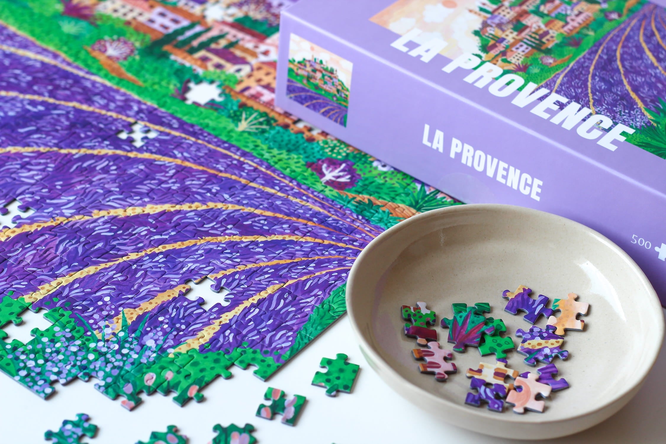 Illustration eines provenzalischen Dorfes auf einem Hügel, umgeben von blühenden Lavendelfeldern bei Sonnenuntergang, als 500-Teile Puzzle von Piecely