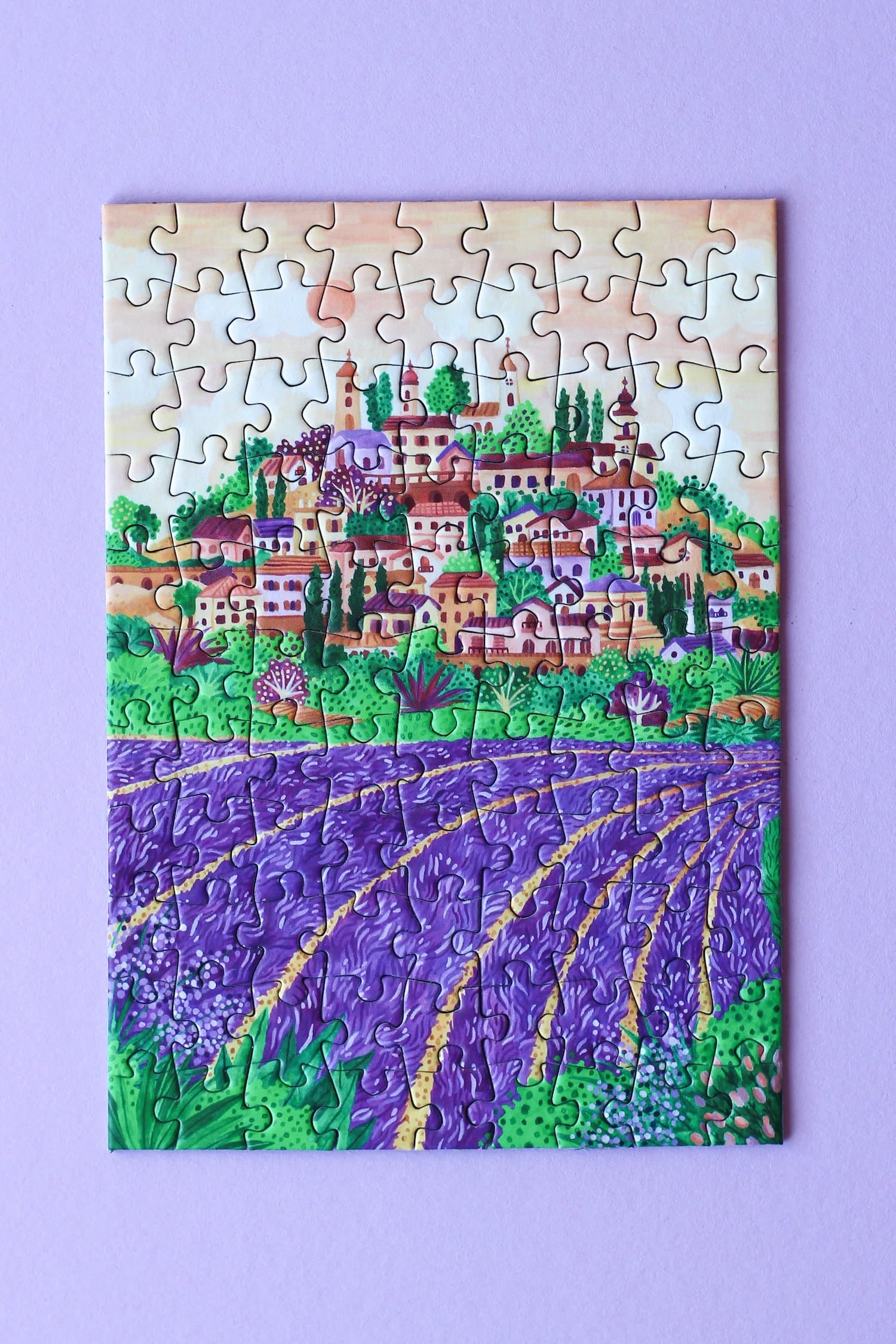Illustration eines provenzalischen Dorfes mit Lavendelfeldern im Sonnenuntergang, als 99-Teile Minipuzzle von Piecely