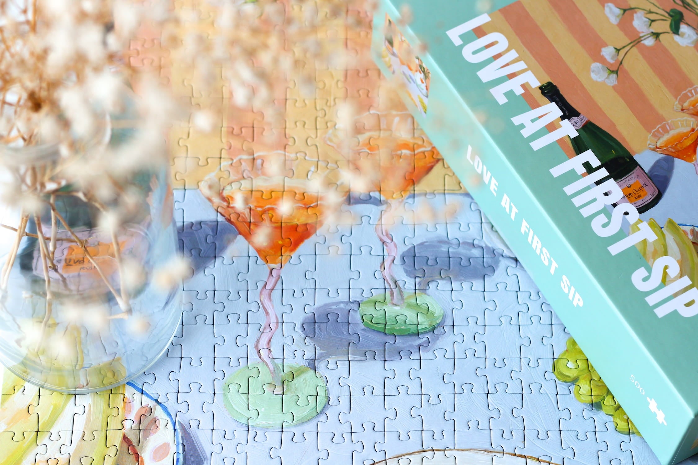 Illustration eines gedeckten Tisches mit Getränken, Orangen, Trauben und Blumen in Vase, als 500-Teile Puzzle ‚Love At First Sip‘ von Piecely