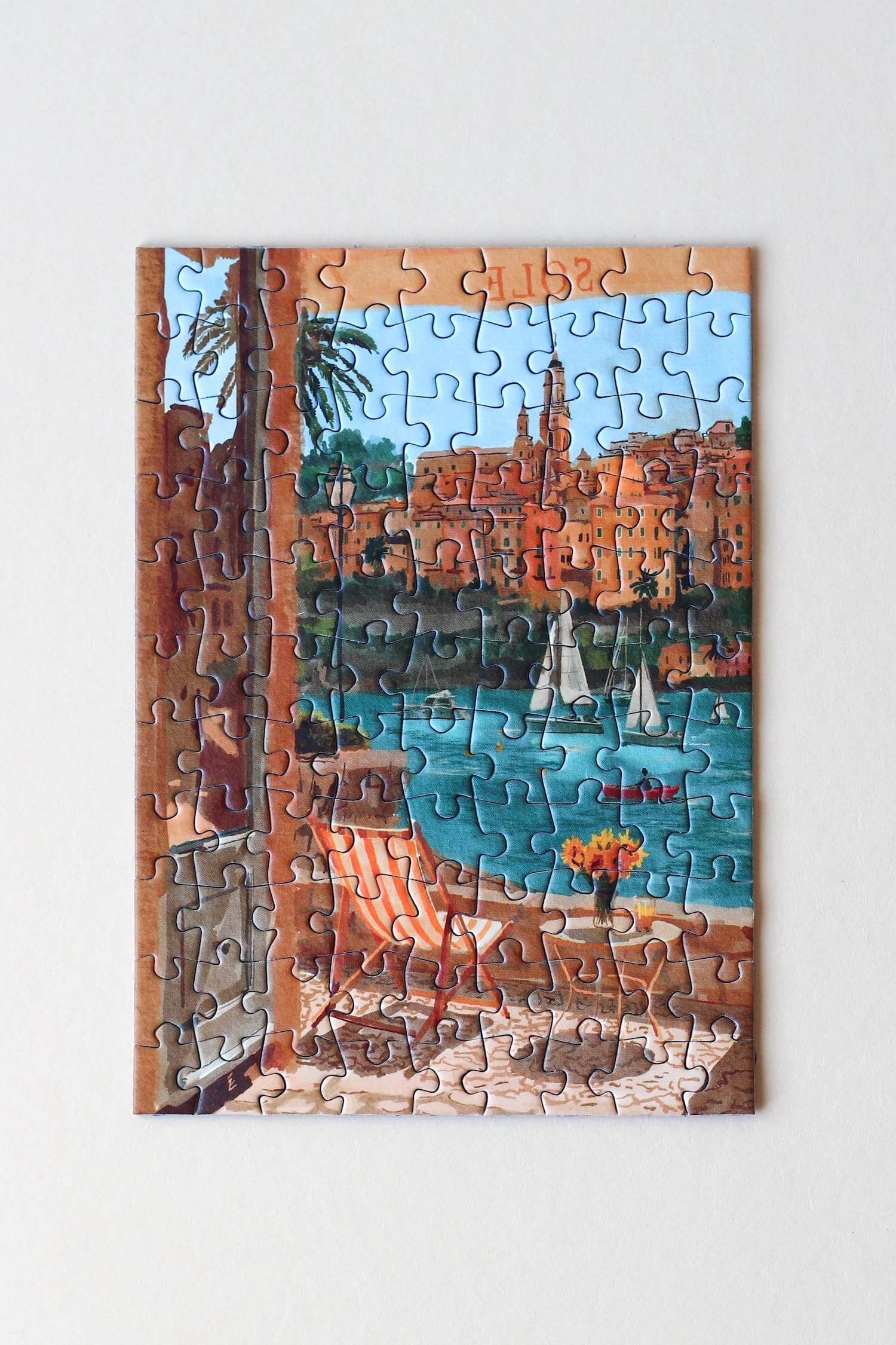 Illustration eines Balkons mit Blick auf Meer, Segelboote und die Stadt Menton in Südfrankreich, als 99-Teile Minipuzzle von Piecely
