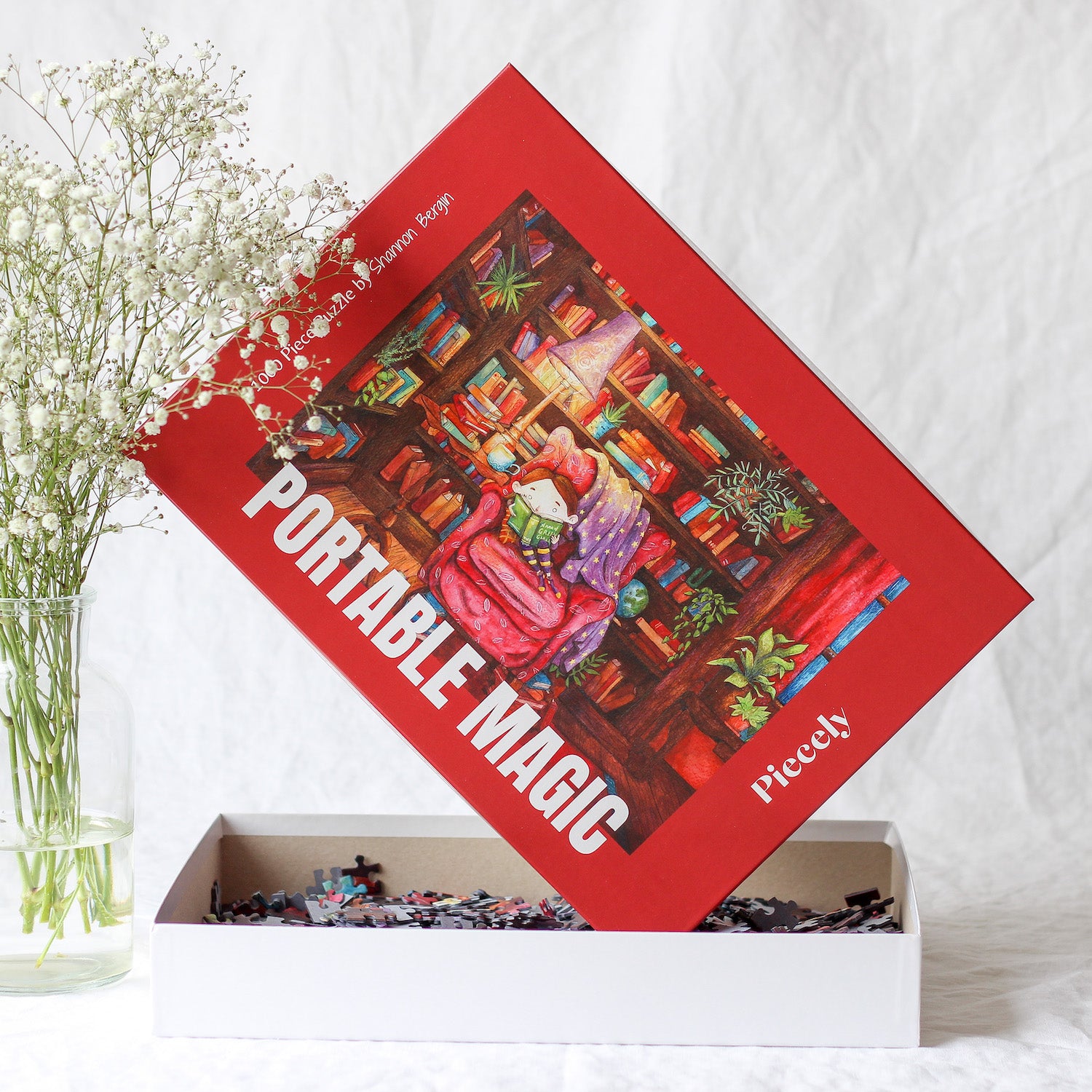 Nachhaltiges 1000-Teile-Puzzle, das ein kleines Mädchen zeigt, das umgeben von hohen Bücherregalen auf einem roten Sessel sitzt und ein Buch liest.