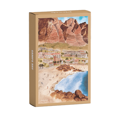 99-teiliges Minipuzzle für Erwachsene, das die Strandpromenade des Kapstädter Viertels Camps Bay zeigt. Im Vordergrund sind man Sandstrand und blaues Meer und im Hintergrund Häuserketten und die Berge.