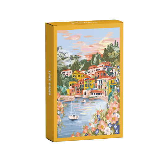 99-teiliges Minipuzzle für Erwachsene, das den Comer See in Varenna zeigt. In der Bucht befinden sich zwei Boote und die Sicht auf den See ist gesäumt von bunten Häusern.