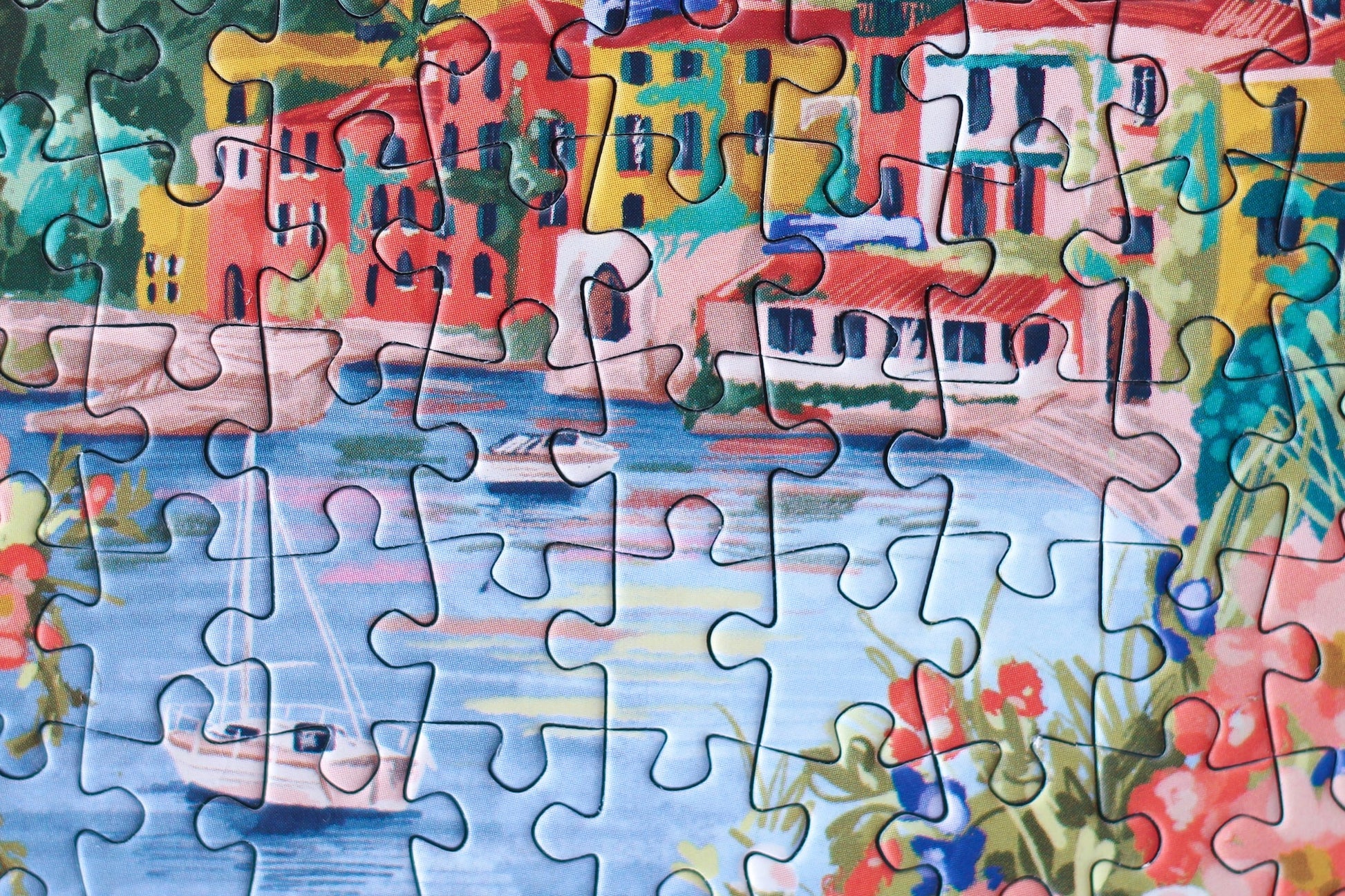 99-teiliges Minipuzzle für Erwachsene, das den Comer See in Varenna zeigt. In der Bucht befinden sich zwei Boote und die Sicht auf den See ist gesäumt von bunten Häusern.
