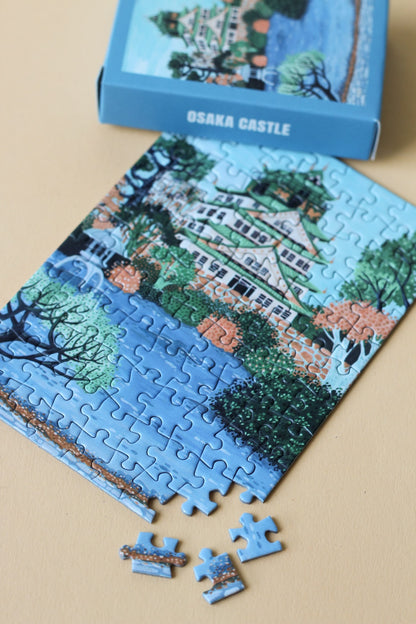 Plastikfreies Minipuzzle für Erwachsene, das die Burg Osaka in Japan in pastelligen Blau- und Grüntönen zeigt. 