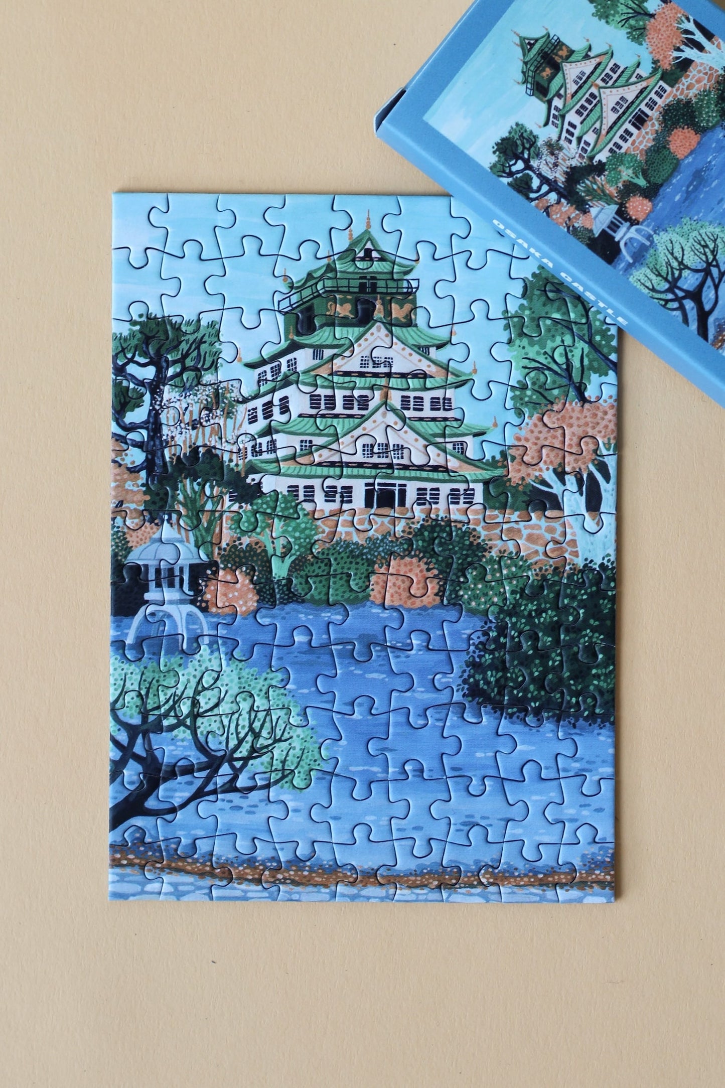 Plastikfreies Minipuzzle für Erwachsene, das die Burg Osaka in Japan in pastelligen Blau- und Grüntönen zeigt.