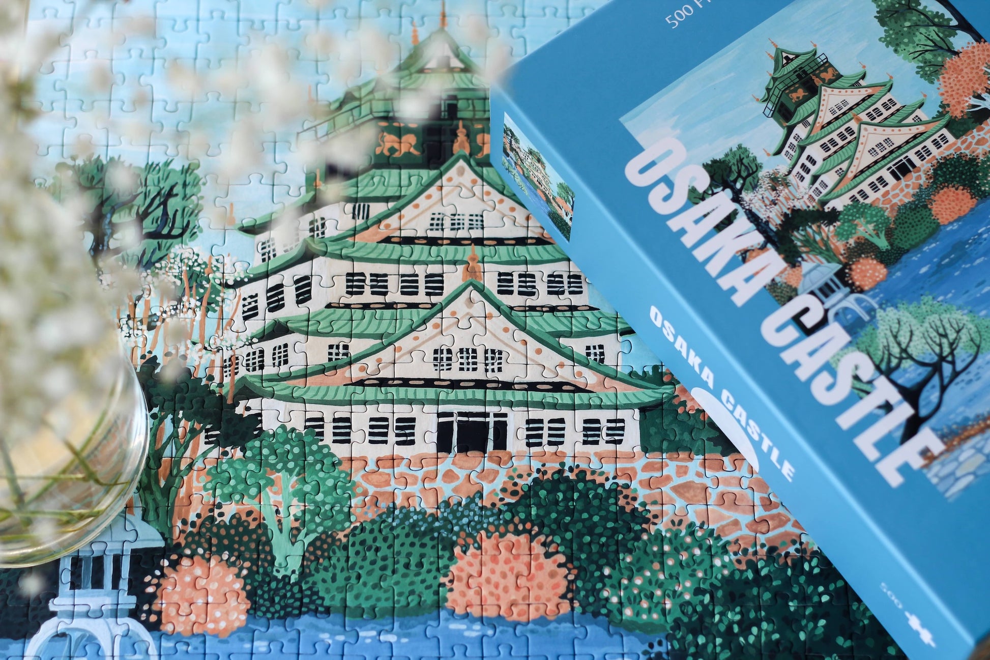 Plastikfreies Puzzle für Erwachsene, das die Burg Osaka in Japan in pastelligen Blau- und Grüntönen zeigt. 