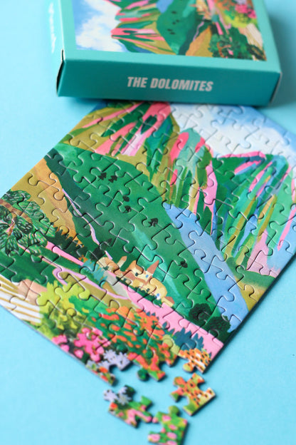 Plastikfreies Minipuzzle für Erwachsene, das die Dolomiten in Italien zeigt. Zu sehen sind ein kleines Dorf, die Berge und ein buntes Blumenmeer