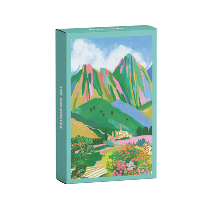 Plastikfreies Minipuzzle für Erwachsene, das die Dolomiten in Italien zeigt. Zu sehen sind ein kleines Dorf, die Berge und ein buntes Blumenmeer